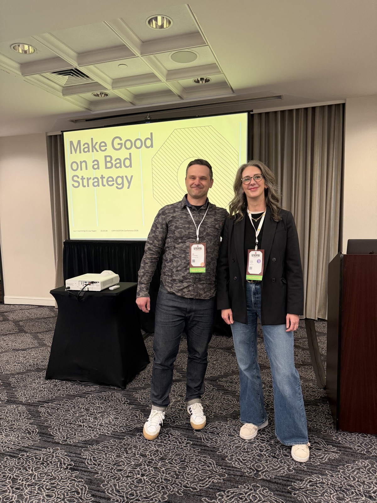 Lisa and Ira standing together in front of the Make Good on a Bad Strategy presentation slide.